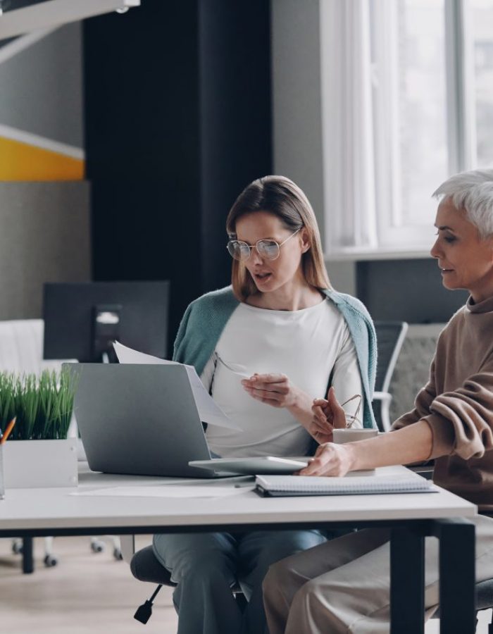 two-confident-women-using-technologies-and-communicating-while-working-in-office-together-e1696735472910.jpg
